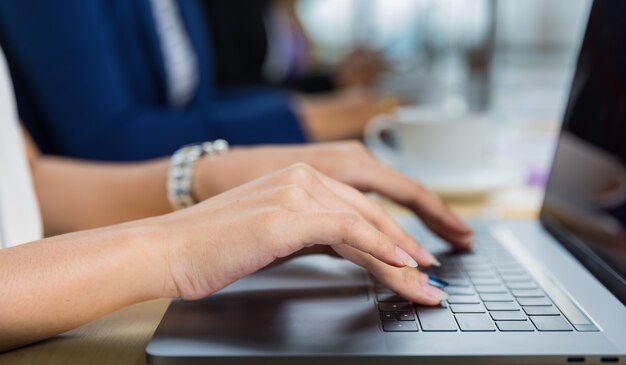 Selectieve focus op de handen van zakenvrouwen die zitten en werken op laptop op vergadertafel in kantoor. Concept voor zakelijke bijeenkomst.