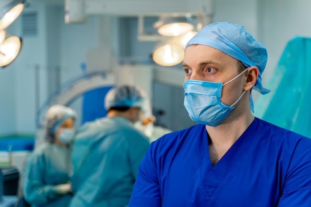 Selectieve focus op dokter in operatiekamer. Masker op het gezicht. Onscherpe achtergrond met werkend team.