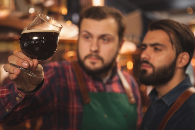 Selectieve focus op een glas donker heerlijk bier in de handen van professionele brouwers