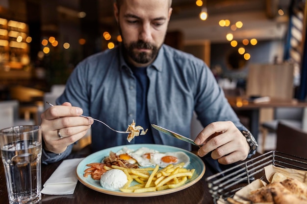 Selectieve focus op handen terwijl de man ontbijt eet in het restaurant