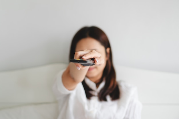 Selectieve focus op jonge vrouw tv kijken en afstandsbediening in de hand te houden.