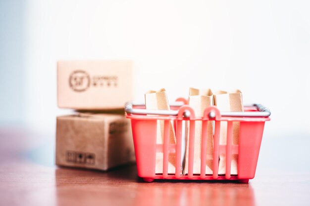 Selectieve focus van de bruine papieren zakken in een rode mand op een houten tafel