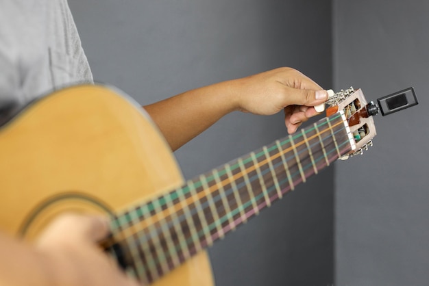 Selectieve focus van de hand van een man die een gitaar stemt tegen een onscherpe achtergrond