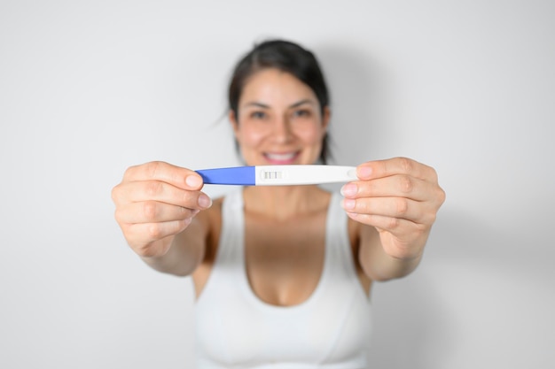 Selectieve focus van de zwangerschapstest gehouden door gelukkige vrouw moederschap concept zwangerschapszorg concept