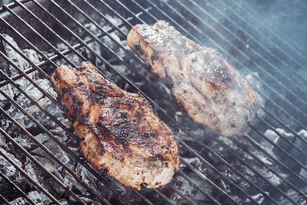 Selectieve focus van sappige steaks die grillen op hete kolen met rook