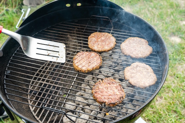 Selectieve focus van verse heerlijke hamburgerkoteletten die op bbq-grill grillen