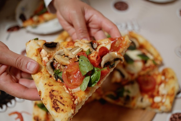 Selectieve focus van vrouwenhanden die een plakje heerlijke, smakelijke zelfgemaakte, versgebakken Italiaanse vegetarische pizza's vasthouden