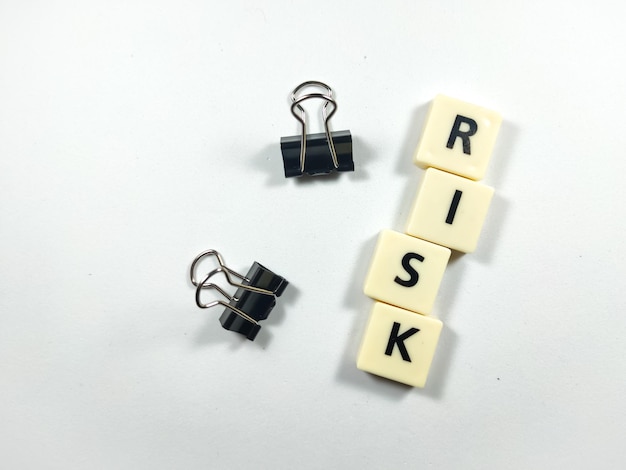 Foto selectieve focusscrabble letters met tekst risico met paperclips op witte achtergrond