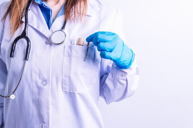 Selectieve weergave van de hand van de arts met toga en stethoscoop en handschoenen die een pen vasthouden om een rapport of medisch bezoekconcept op recept te schrijven