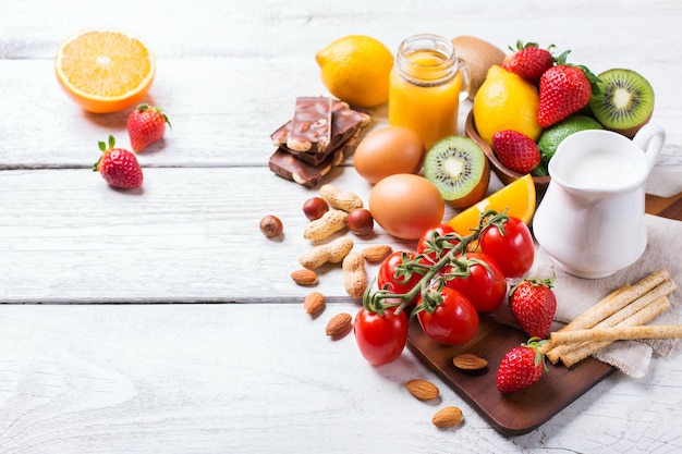 Selection of allergy food orange citrus juice milk red tomato strawberry kiwi eggs chocolate nuts bread gluten on a rustic wooden table Copy space background