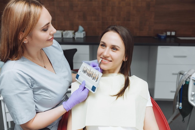 Selection of the correct tooth color for professional cosmetic whitening at the dentist the doctor selects the teeth for the patient