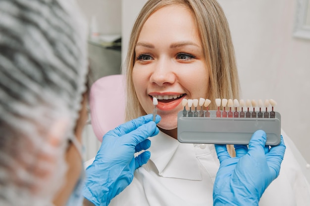 歯科医でのプロの化粧品ホワイトニングのための正しい歯の色の選択。医師は患者の歯を選択します。