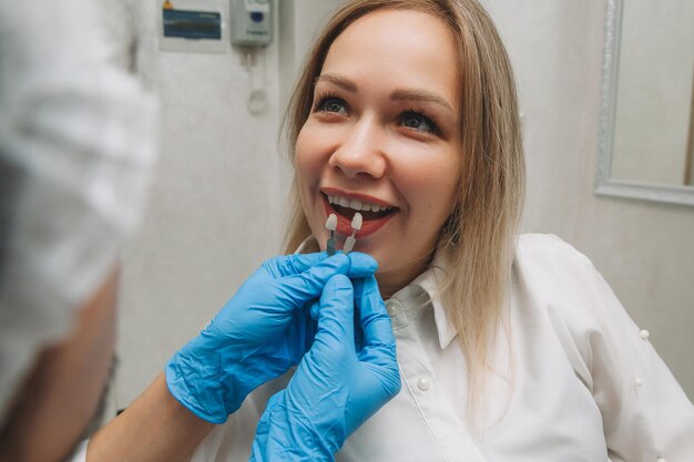 Selezione del colore dei denti corretto per lo sbiancamento cosmetico professionale dal dentista. il medico seleziona i denti per il paziente.