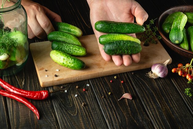 Selection of cucumbers by the hands of the cook for preservation or pickling in a jar Work environment on the kitchen table Peasant food