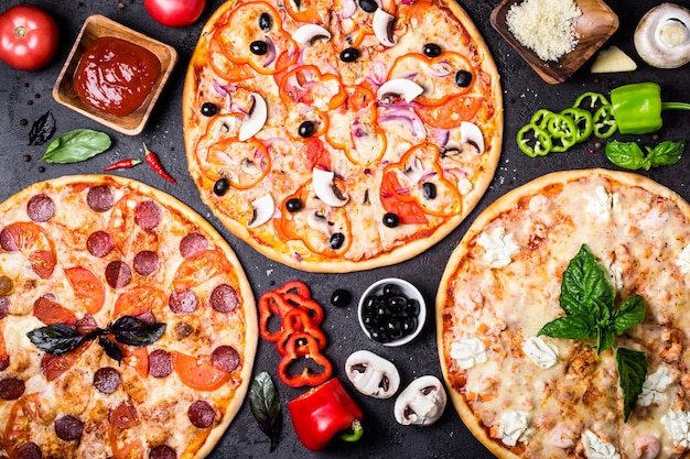 Foto selezione di diverse pizze su fondo nero e ingredienti peperoni pizza vegetariana e di pesce