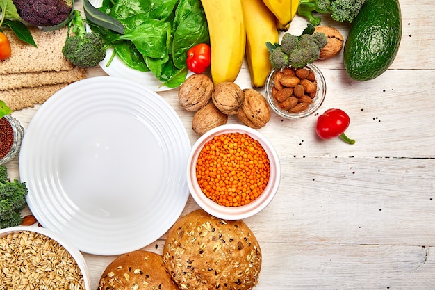 Selection food rich in fiber on white wooden background around empty plate