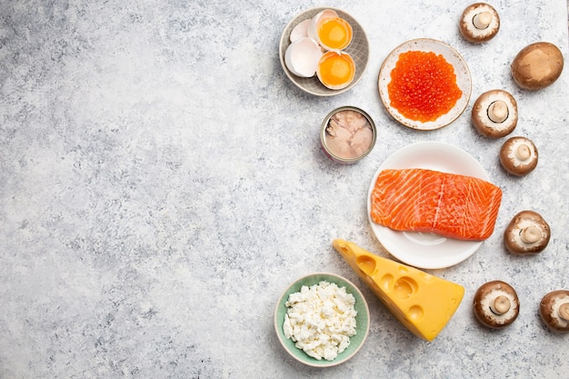 Selection of natural sources of vitamin D: fresh salmon; caviar; cheese; mushrooms; tuna; eggs on white stone background top view. Assorted foods and products rich in vitamin D; from above; copy space