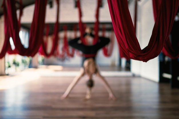 Selective focus of aerial yoga swings on background of an flexible female practicing a pose