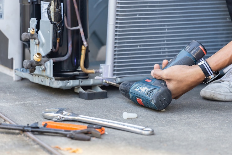 Photo selective focus air conditioning repair, technician man hands using a screwdriver fixing modern air conditioning system