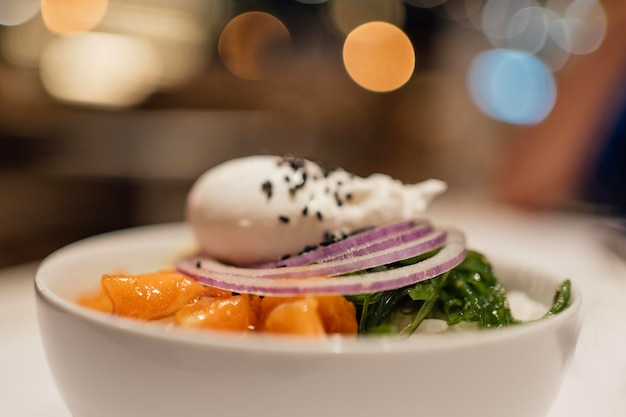 Selective focus Asian salmon poke bowl with blurred background party night lights