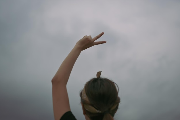 写真 セレクティブ・フォーカス バック・ビュー・ポイント 若い女性が頭の上に勝利のサインを示す インスピレーション 動機付け