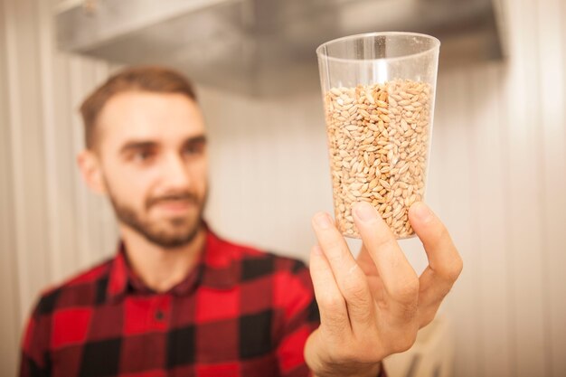 Photo selective focus on barley seeds in a glass male brewer is examining