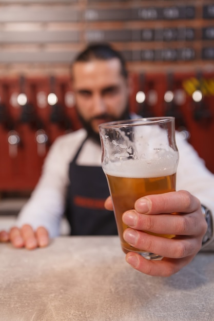 Selective focus on beer glass in the hands of bartender