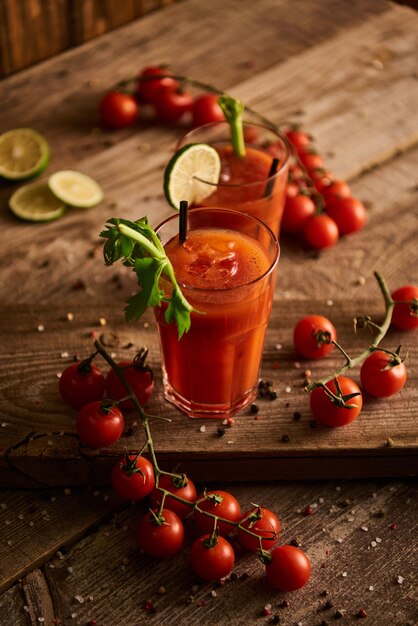 Selective focus of bloody mary cocktail in glasses on wooden background with salt pepper tomatoes