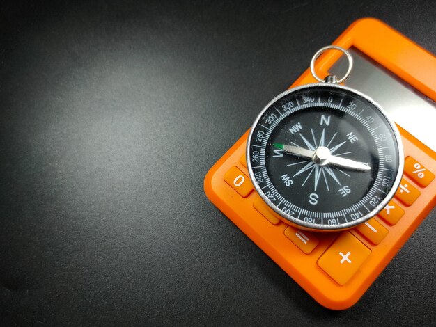 Selective focus of calculator and compass on black background with Copy space