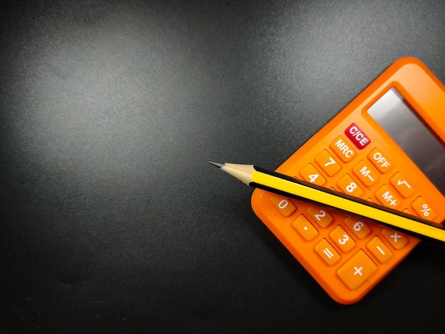 Selective focus of calculator and pencil on black background with Copy space