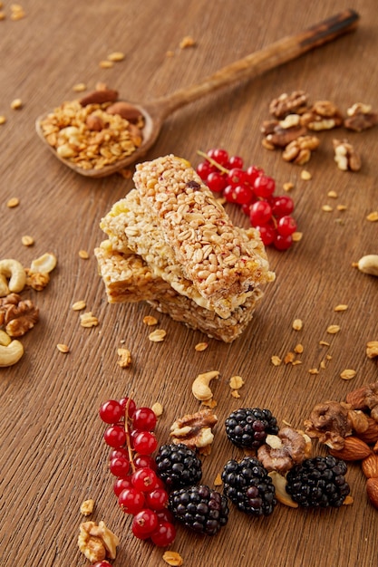 Selective focus of cereal bars spatula with granola redcurrants blackberries and nuts on wooden