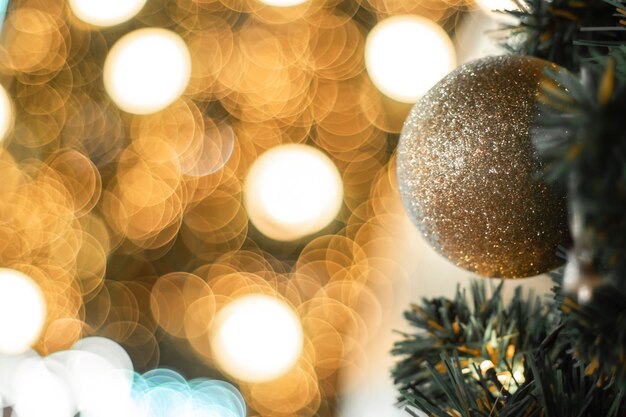 Selective focus Christmas tree with holiday gold ball and lights with copy space on blurred bokeh background