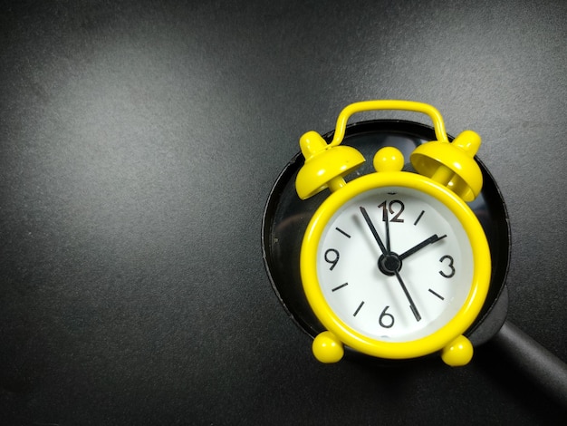 Selective focus of clock and magnifying glass on black background with copy space