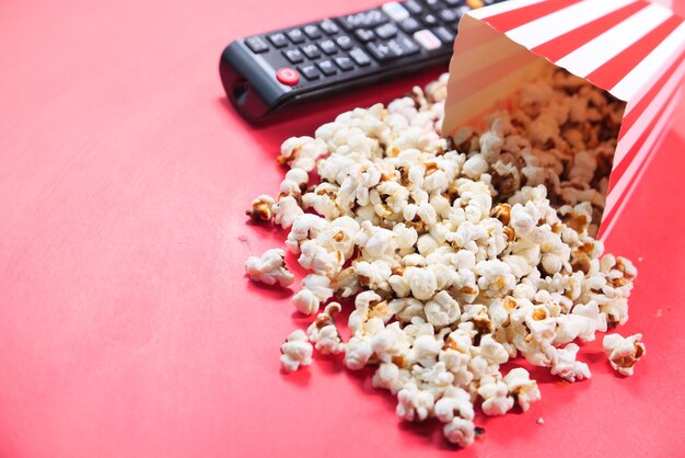 Selective focus. close up of popcorn and Tv remote on red background