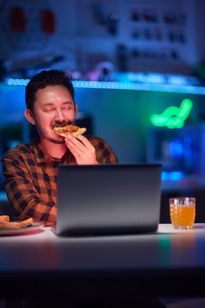 Photo selective focus on delicious pizza cheerful man is taking from the box program developer resting from working taking a piece of pizza