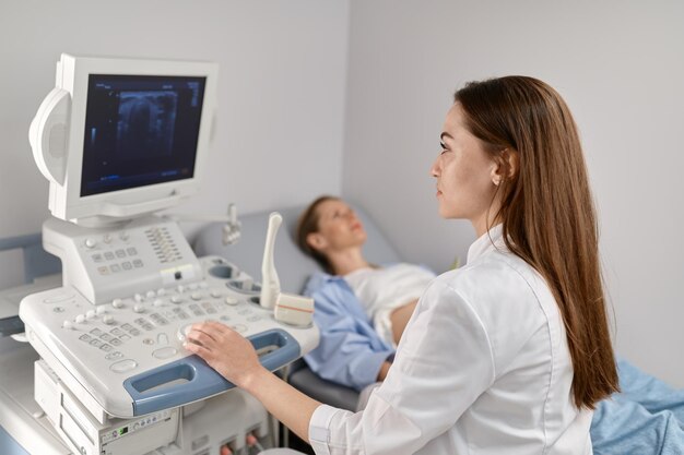 Photo selective focus doctor doing ultrasound of fetus to pregnant woman in modern prenatal clinic office