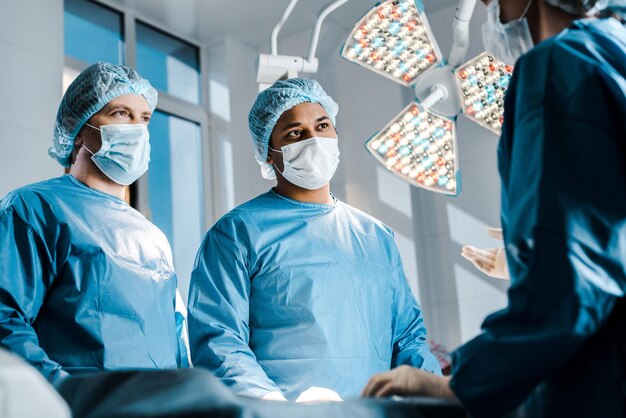 selective focus of doctors and nurse in uniforms and medical masks talking