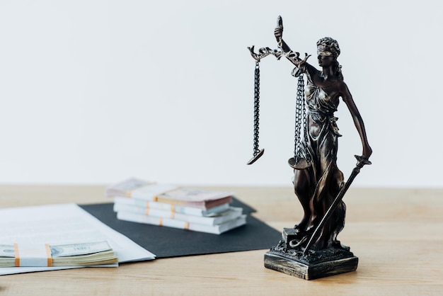 Selective focus of dollar banknotes on folder near statuette of justice