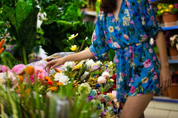 여름 드레스를 사는 여자와 꽃집의 꽃과 식물에 선택적 초점