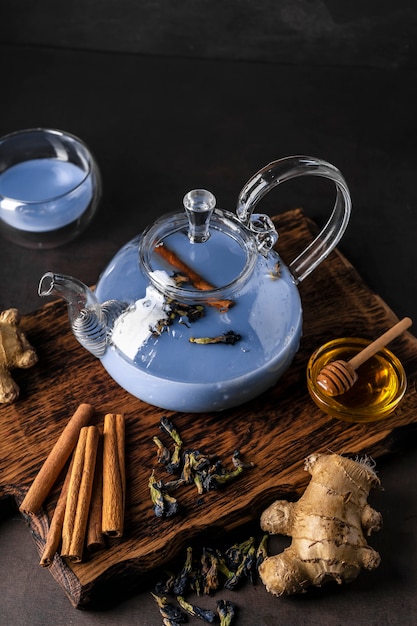 Selective focus freshly brewed blue masala tea in a transparent teapot with fruits and fresh berries...