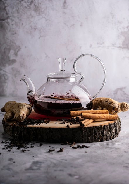 Фото Селективный фокус свежезаваренного чая в прозрачном чайнике с фруктами и свежими ягодами листового чая и ...