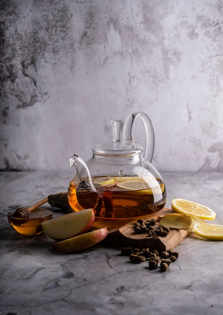 Selective focus freshly brewed tea in a transparent teapot with fruits and fresh berries leaf tea an...