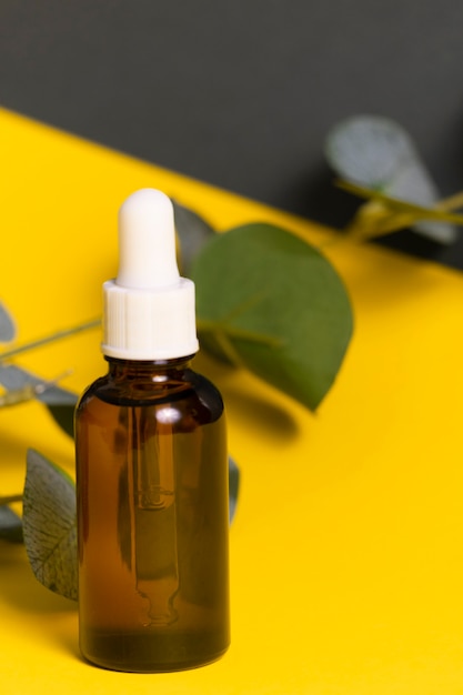 Selective focus. a glass jar with a pipette. inside is a cosmetic organic oil for the skin of the face and body. on a yellow-gray paper background. copyspace