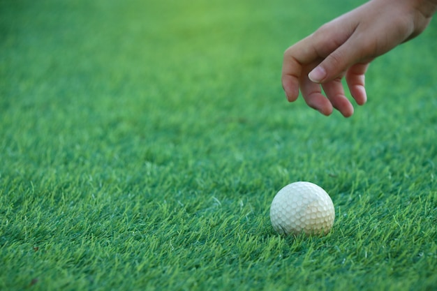 La mano del fuoco selettivo del carrello del bambino sta raggiungendo per la pallina da golf su verde. per continuare a raggiungere l'obiettivo