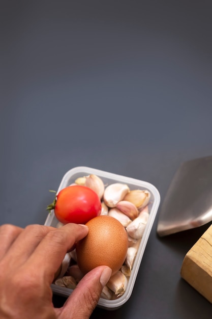 Selective focus of hand held eggs with tomatoes and garlic in a