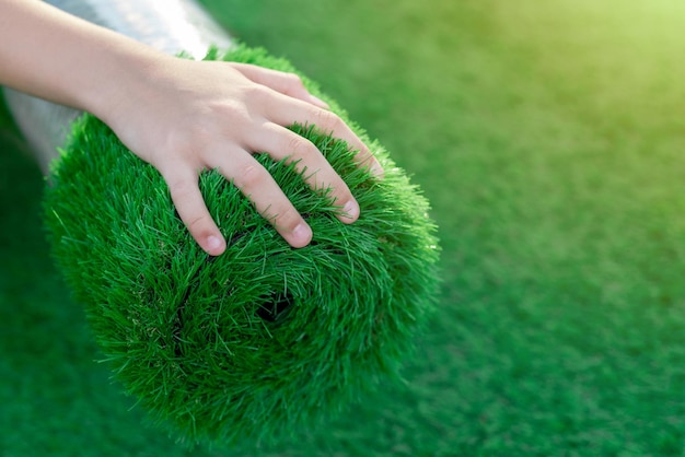 Selective focus hand stroking roll of soft squishy artificial turf economical green lawn alternative