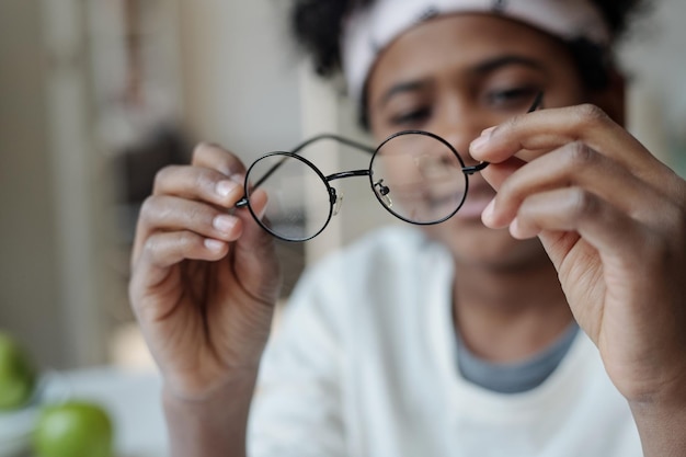 Selective focus on hands of African American boy holding eyeglasses