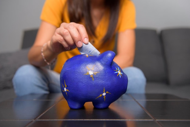 selective focus of happy latin couple inserting money into piggy bank to save their money