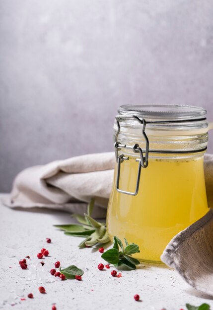 Selective focus. Homemade Beef Bone Broth in a glass jar. on a light gray background. with the addition of spices-salt and pepper. Bones contain collagen, which provides the body with amino acids