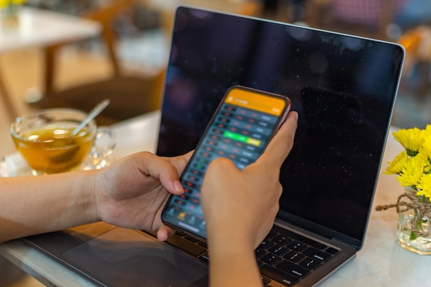 Photo selective focus image of human using smartphone checking stock exchange index